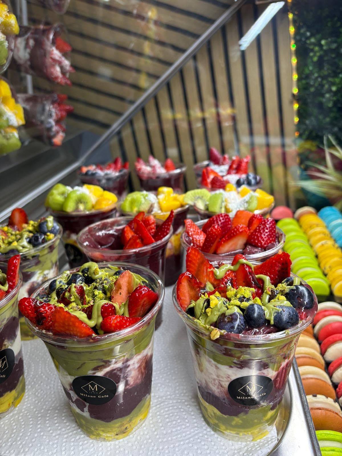 Acai Bowls mit Pistazie, Erdbeeren und Heidelbeeren in Milano-Bechern an der Theke