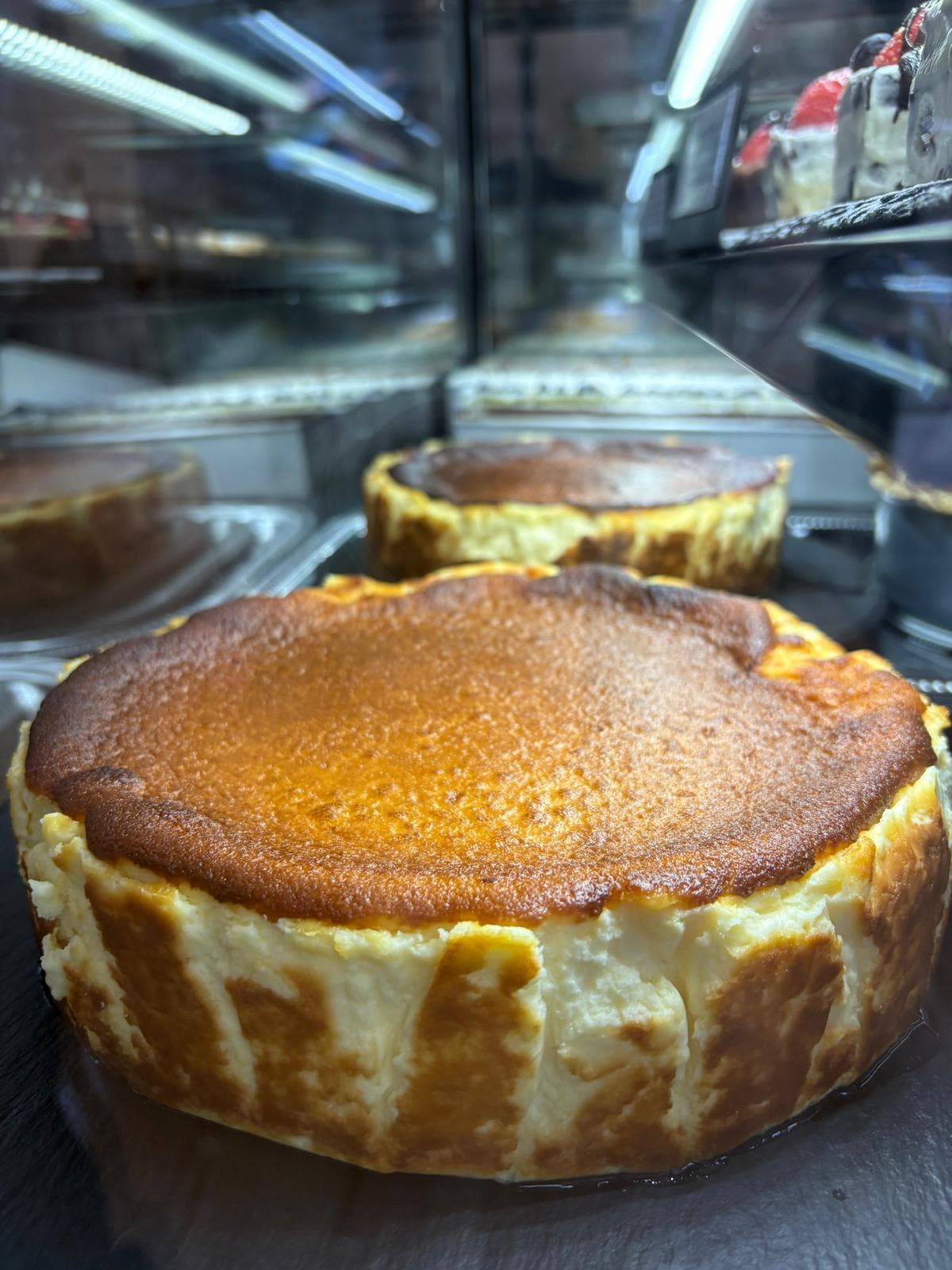 Ganzer gebackener Cheesecake in der Kuchenvitrine
